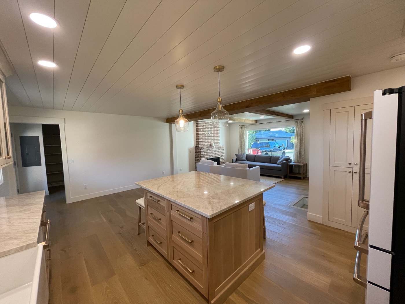 Kitchen with large stone island, wood plank ceiling and open living room