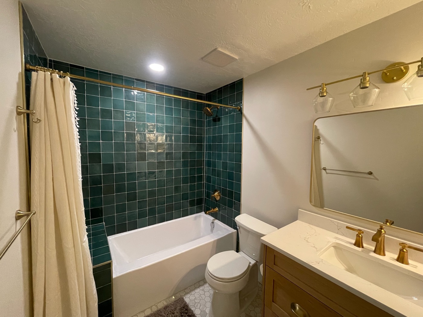 Bathroom with green tile tub surround and brass fixtures